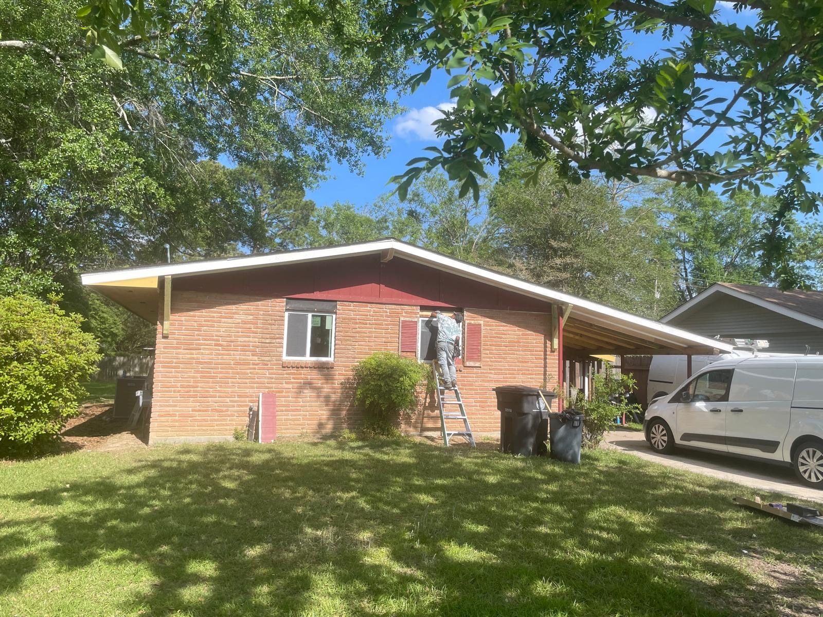 Painter on ladder, brick home trim