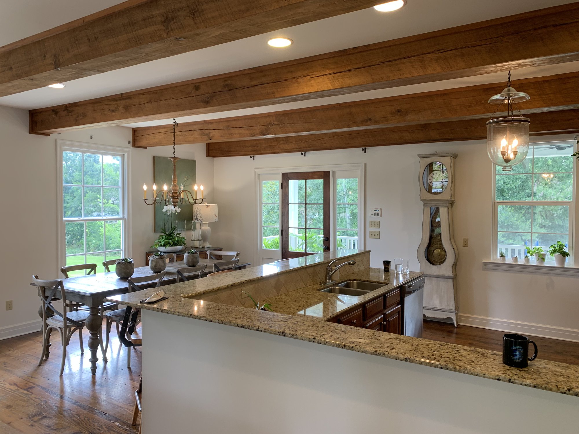 Open kitchen and dining with exposed wood beams and granite island